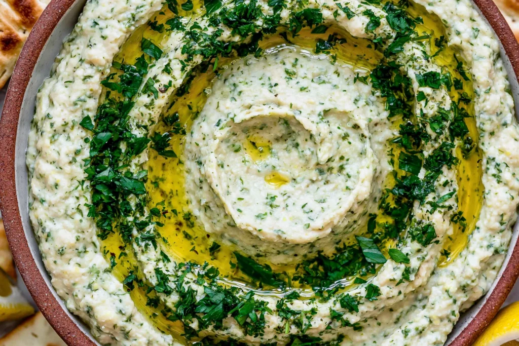 Close-up of creamy Lemon & Herb White Bean Dip garnished with fresh parsley and extra virgin olive oil, served as a healthy Mediterranean appetizer.