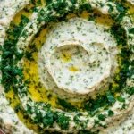 Close-up of creamy Lemon & Herb White Bean Dip garnished with fresh parsley and extra virgin olive oil, served as a healthy Mediterranean appetizer.