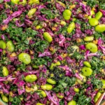 Longevity Miso Bowl salad with kale, red cabbage, edamame, black sesame seeds, and miso-ginger dressing in a green bowl