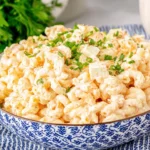 Creamy Macaroni Hawaiian Salad in a blue patterned bowl, topped with chopped herbs and green onions, with tender elbow macaroni and a rich mayo dressing.