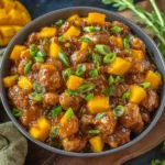 Bowl of Mango Chicken Stir Fry with crispy chicken bites, glossy sweet-spicy sauce, fresh mango cubes, and sliced green onions.