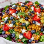 Strawberry Avocado Corn Salad with grilled corn, strawberries, blueberries, goat cheese, and greens, drizzled with honey mustard vinaigrette.