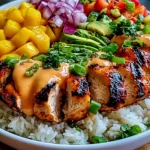 Chicken Mango Rice Bowl with grilled chicken, fresh mango, avocado, red onion, cucumber, rice, herbs, and spicy creamy sauce.