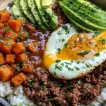 Hot Honey Ground Beef Bowls with rice, roasted sweet potatoes, avocado, a fried egg, fresh herbs, and spicy hot honey sauce.