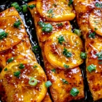 Orange Glazed Salmon fillets in a skillet with caramelized orange slices, sesame seeds, green onions, and fresh parsley.