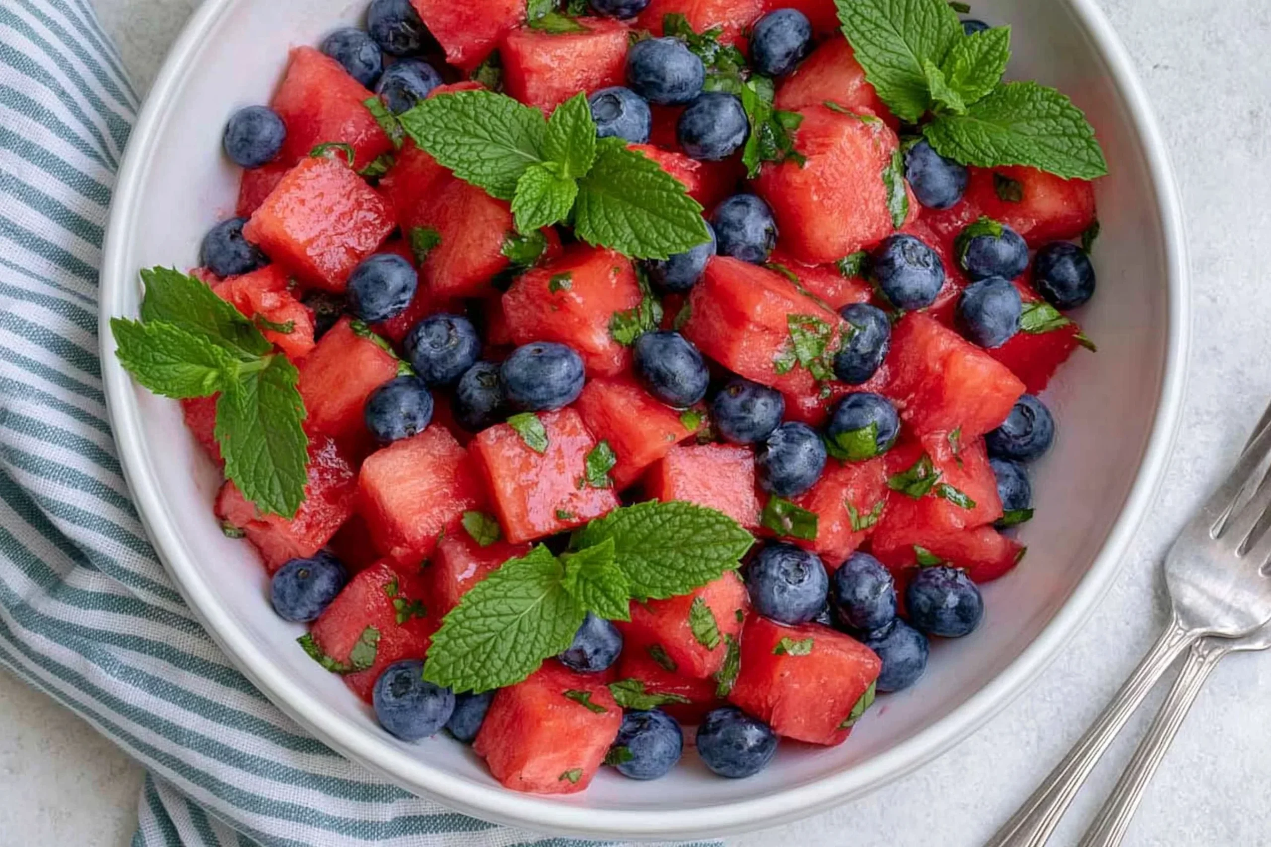 Watermelon Blueberry Salad with fresh mint in a white bowl, a refreshing summer fruit salad with honey lime dressing
